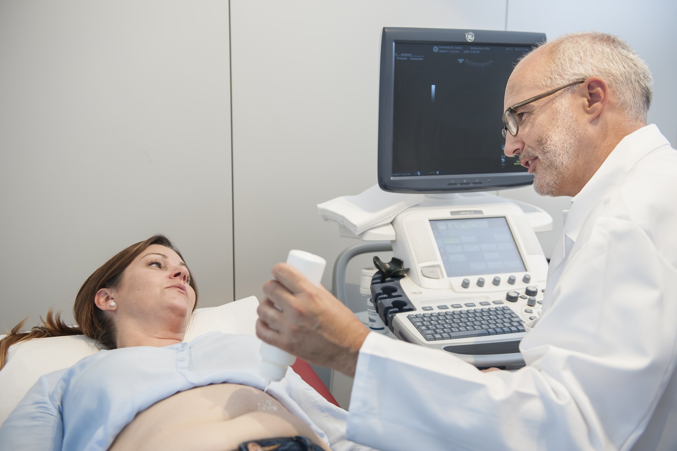 Arzt im Gespräch mit Patienten beim Ultraschall.