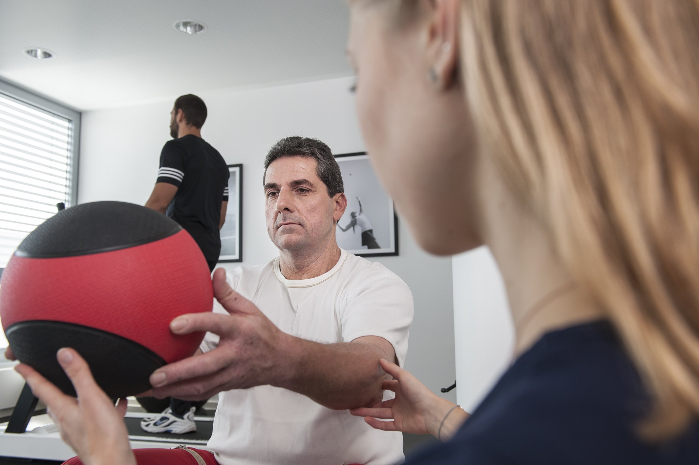 Ein Mann bei physiotherapeutischen Übungen mit einem Ball zur Wiederherstellung der Arbeitsfähigkeit.